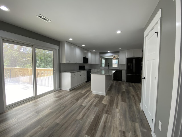 kitchen featuring dark hardwood / wood-style floors, sink, a center island, black appliances, and plenty of natural light