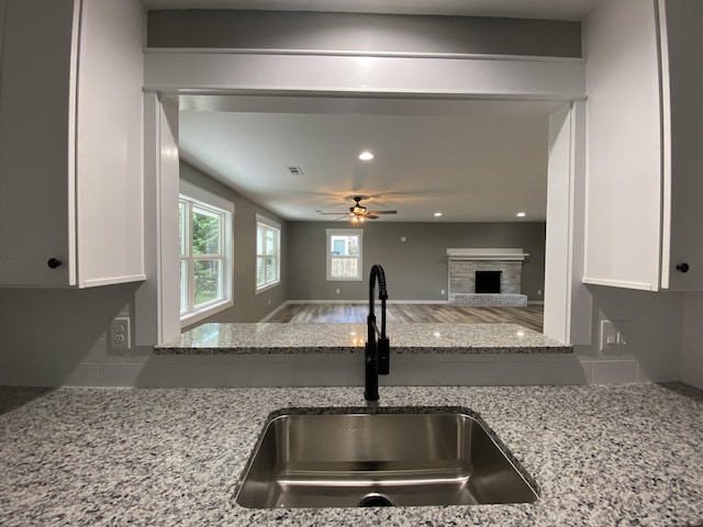 kitchen featuring white cabinets, light stone countertops, and sink