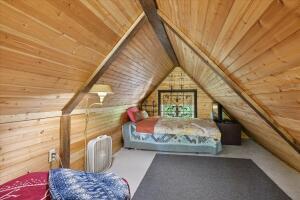 bedroom with vaulted ceiling, wood ceiling, and wooden walls