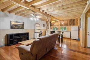 living room featuring a glass covered fireplace, wooden ceiling, beamed ceiling, and wood finished floors