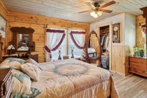 bedroom with a closet, wood walls, wooden ceiling, and wood finished floors