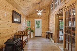 entryway featuring wood-type flooring, wood ceiling, vaulted ceiling, wooden walls, and ceiling fan