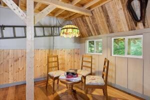 sitting room with wood walls, vaulted ceiling, and wood finished floors