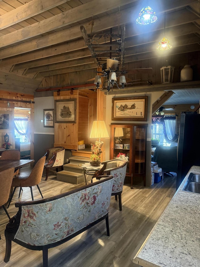 living room with vaulted ceiling with beams, wooden ceiling, wood finished floors, and wooden walls