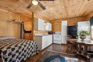 bedroom featuring dark wood-style floors, freestanding refrigerator, wooden ceiling, and wood walls