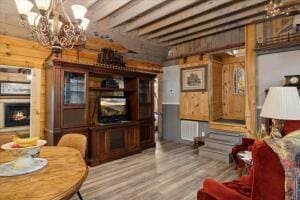 living room with a warm lit fireplace, a chandelier, and wood finished floors