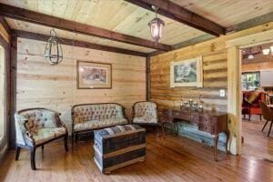 sitting room featuring wooden ceiling, log walls, wood finished floors, and beamed ceiling