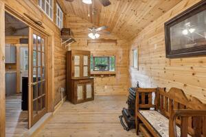 hallway featuring vaulted ceiling, wood walls, wood finished floors, and wood ceiling