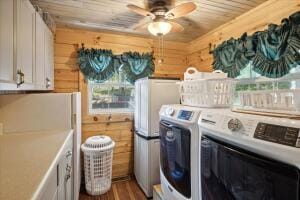 clothes washing area with wooden ceiling, independent washer and dryer, a ceiling fan, and wooden walls