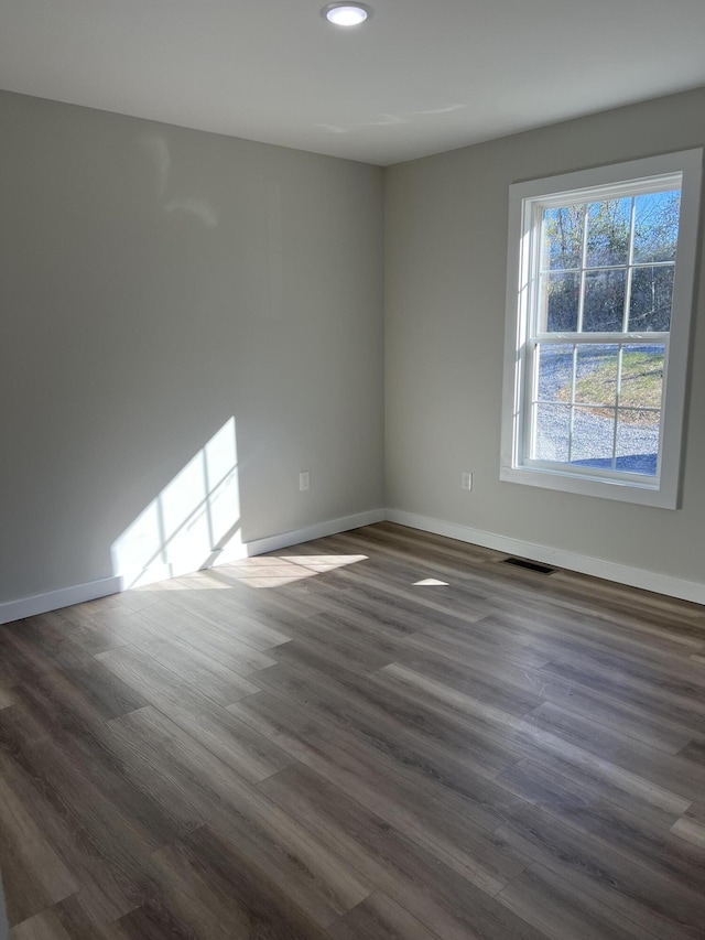 empty room with dark wood-type flooring, recessed lighting, visible vents, and baseboards