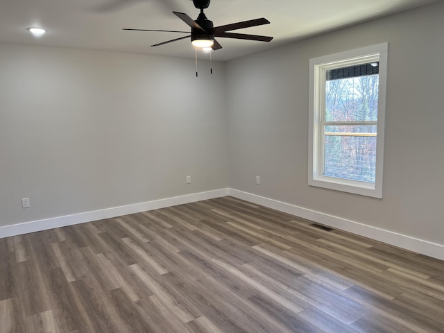 unfurnished room with ceiling fan, dark wood-type flooring, visible vents, and baseboards