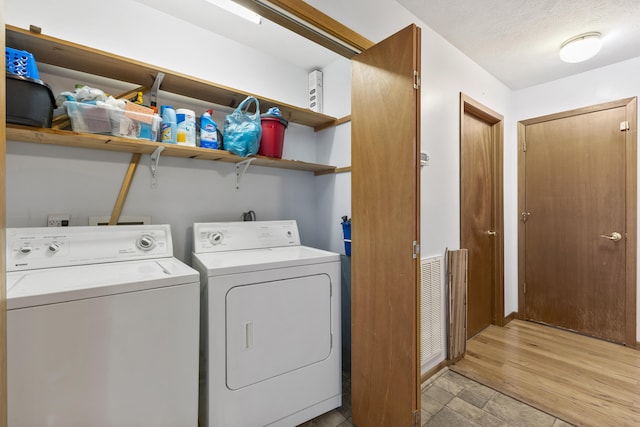 washroom featuring a textured ceiling, washer and dryer, and light wood-type flooring