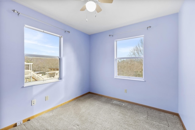 carpeted spare room featuring ceiling fan and plenty of natural light