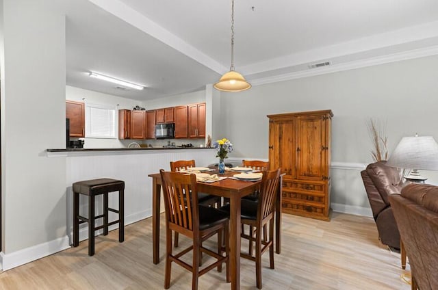 dining room with baseboards, visible vents, and light wood finished floors