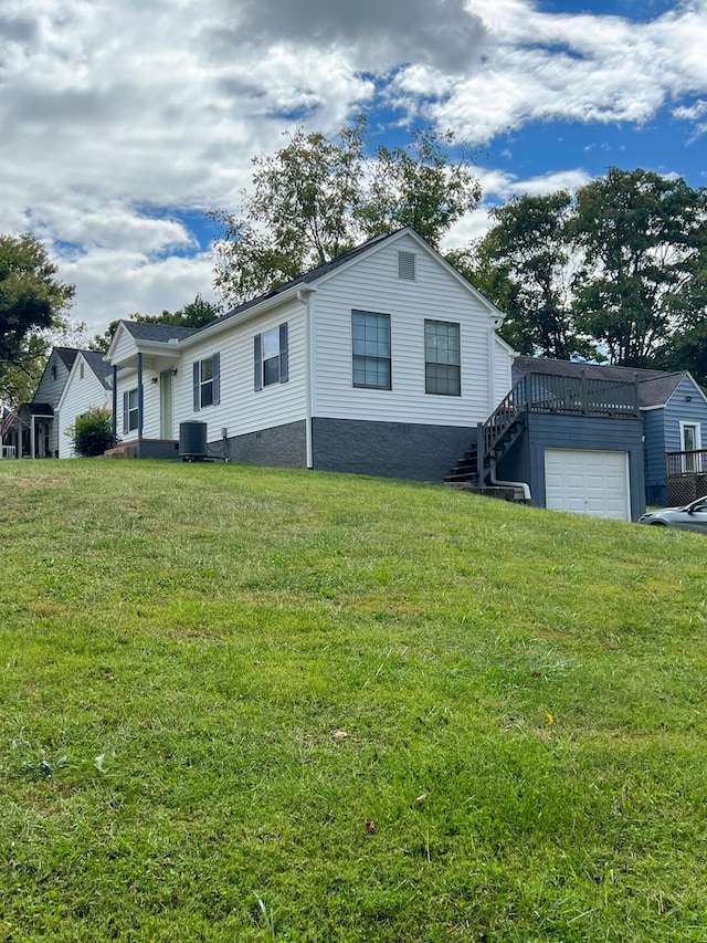 view of front of property with a garage, a front lawn, and central air condition unit