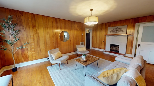 living room with hardwood / wood-style flooring, a notable chandelier, and wood walls