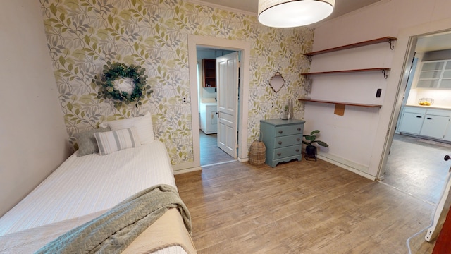 bedroom featuring connected bathroom, light hardwood / wood-style flooring, and ornamental molding