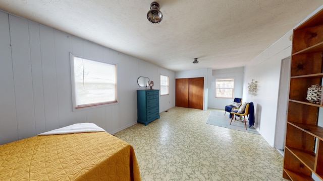 bedroom featuring a textured ceiling and wooden walls