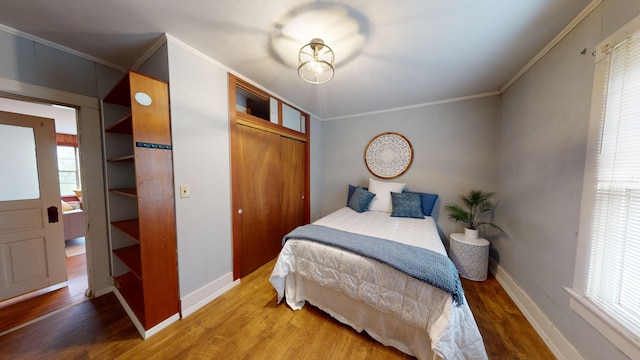 bedroom with a closet, crown molding, and hardwood / wood-style floors