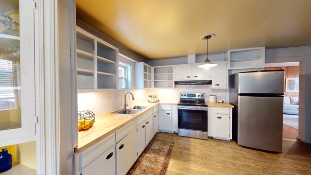 kitchen with tasteful backsplash, stainless steel appliances, sink, white cabinetry, and hanging light fixtures