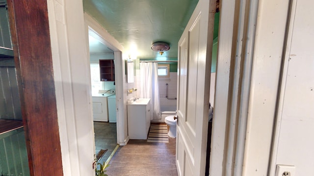 hall featuring dark hardwood / wood-style flooring, sink, and washing machine and clothes dryer