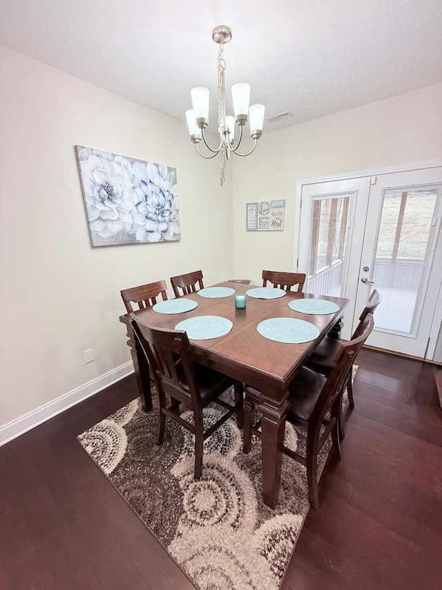 dining room with dark hardwood / wood-style floors, an inviting chandelier, and french doors