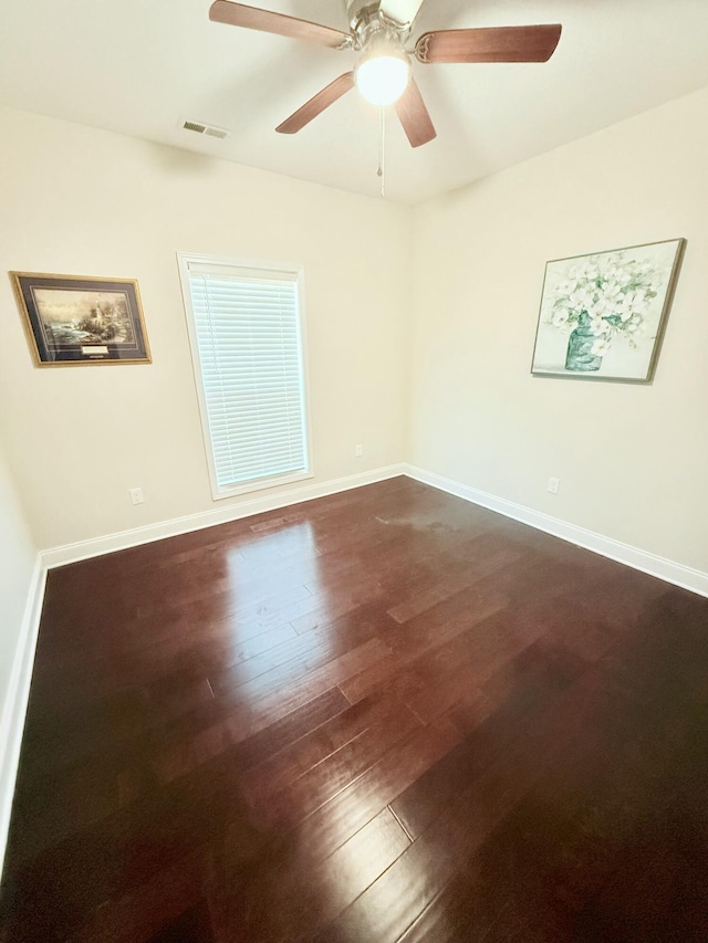 spare room with dark hardwood / wood-style flooring and ceiling fan