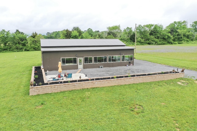 rear view of house featuring a lawn, metal roof, and a patio