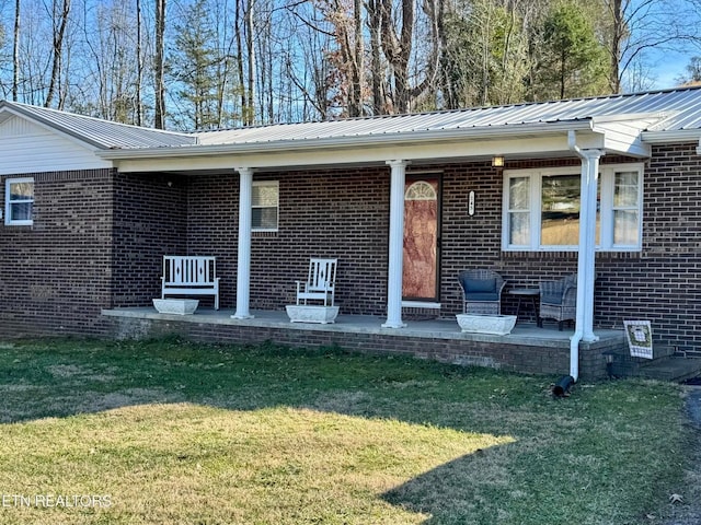 property entrance featuring metal roof, brick siding, and a lawn