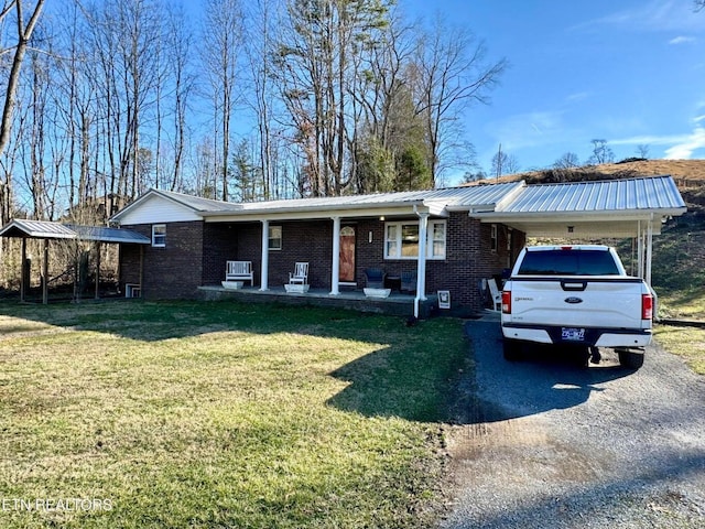 ranch-style home with a porch, a carport, a front lawn, brick siding, and metal roof