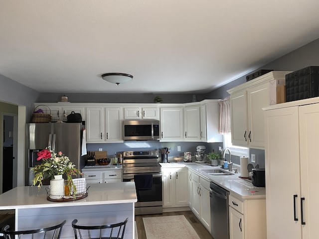 kitchen with stainless steel appliances, light countertops, a sink, and a kitchen breakfast bar