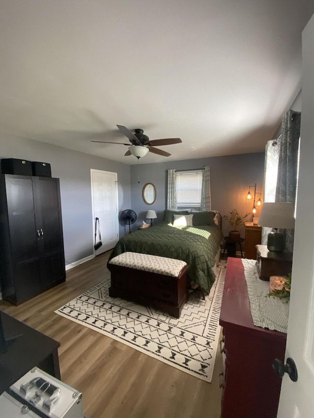 bedroom featuring ceiling fan, baseboards, and wood finished floors