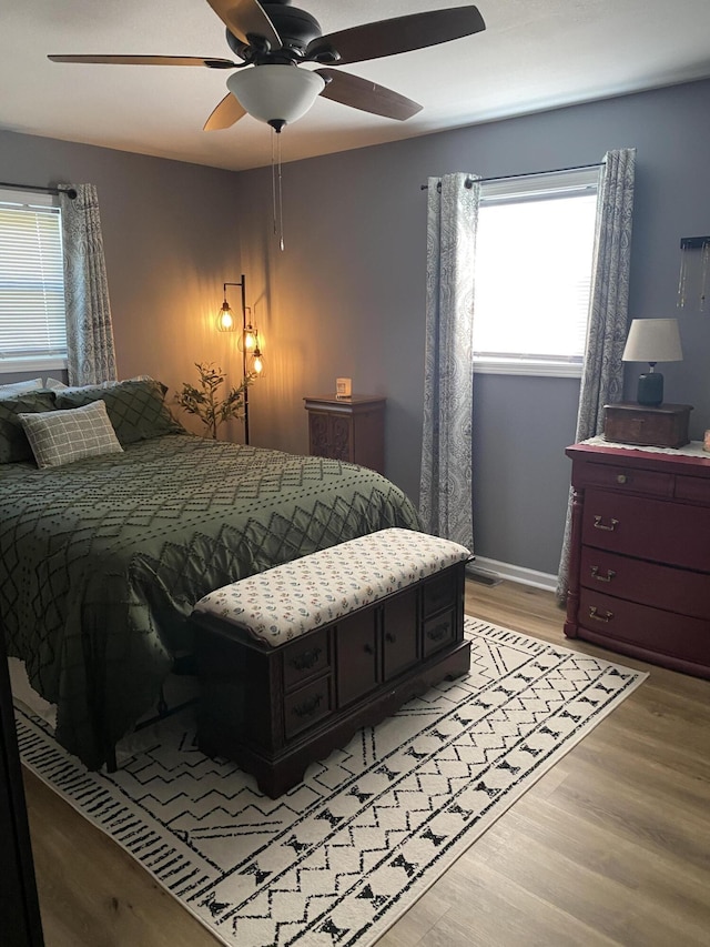 bedroom with a ceiling fan, light wood-style flooring, and baseboards