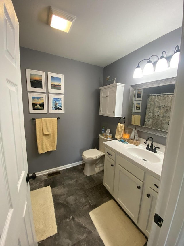 bathroom featuring vanity, toilet, and baseboards