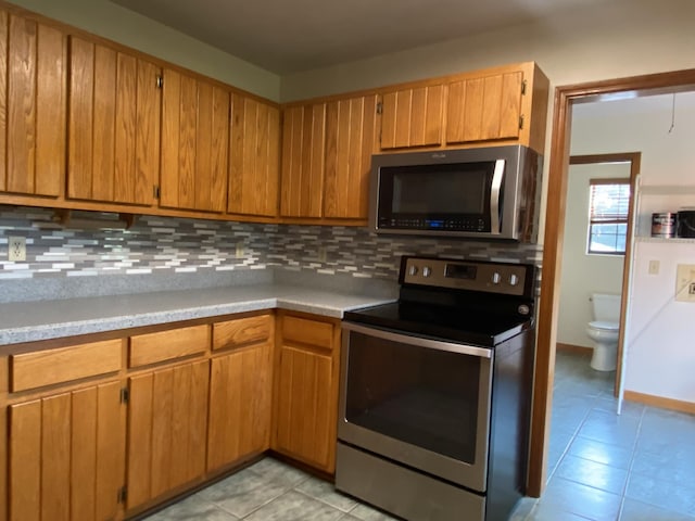 kitchen with light tile patterned floors, backsplash, and stainless steel appliances