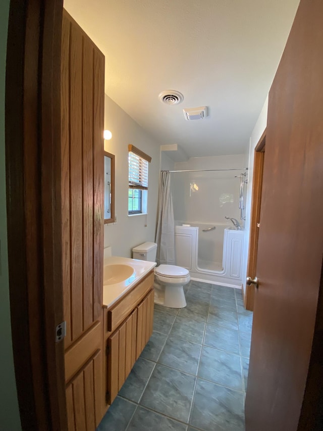 bathroom with a shower with curtain, vanity, toilet, and tile patterned floors