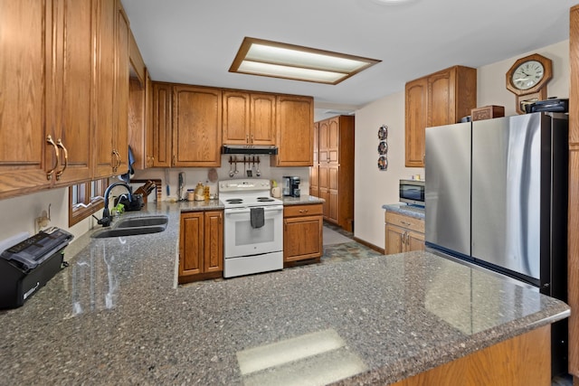 kitchen with stainless steel appliances, dark stone counters, and sink