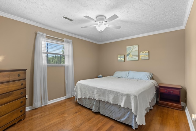 bedroom with a textured ceiling, wood finished floors, visible vents, and crown molding