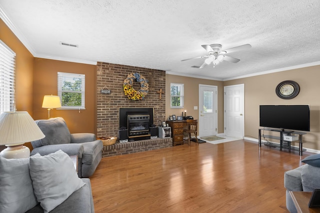 living area featuring a textured ceiling, ceiling fan, wood finished floors, visible vents, and crown molding