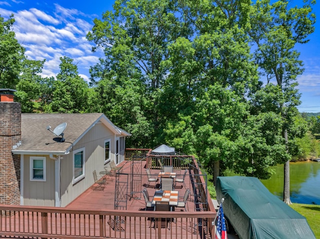 wooden deck with outdoor dining space and a water view