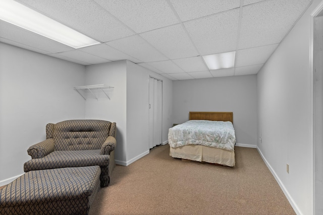 bedroom featuring baseboards, a drop ceiling, and carpet flooring