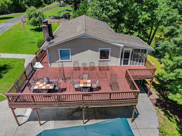 rear view of house featuring outdoor dining space, a sunroom, a chimney, and a wooden deck