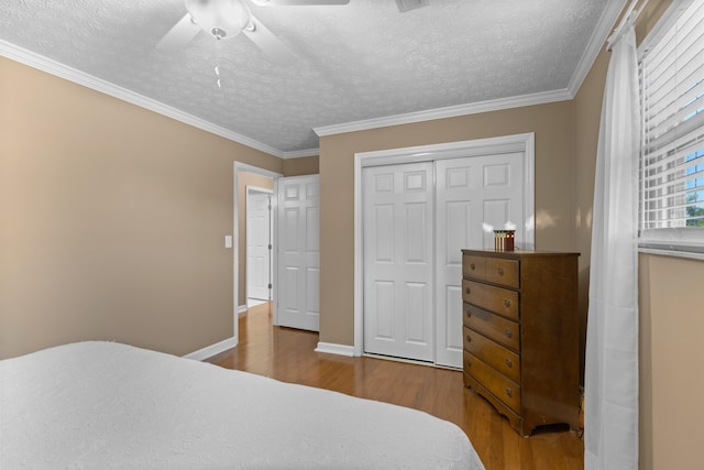 bedroom with ornamental molding, a closet, a textured ceiling, and wood finished floors