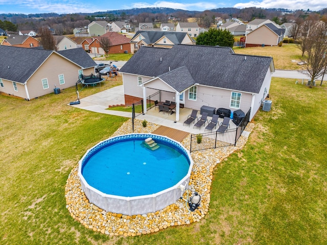 view of swimming pool featuring a trampoline, outdoor dining area, a patio area, central AC, and a residential view