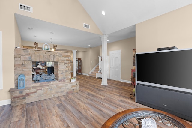 unfurnished living room with hardwood / wood-style floors, high vaulted ceiling, a stone fireplace, and a notable chandelier