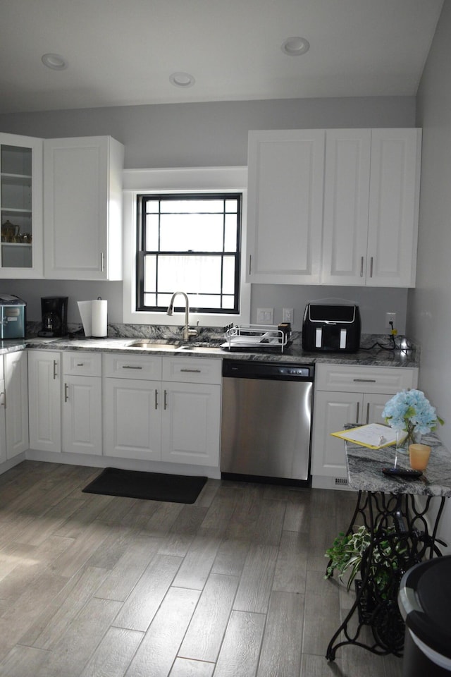 kitchen featuring sink, white cabinetry, dark stone countertops, dishwasher, and light hardwood / wood-style floors