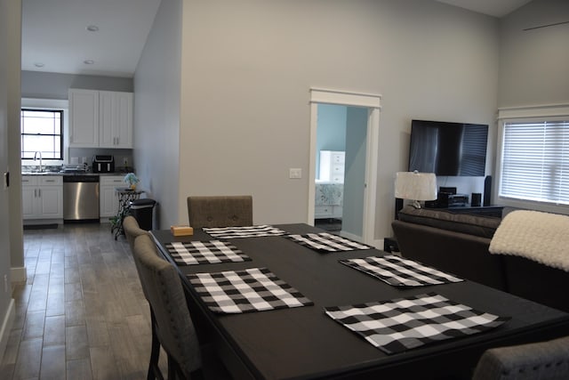 dining area with sink, a towering ceiling, and dark wood-type flooring