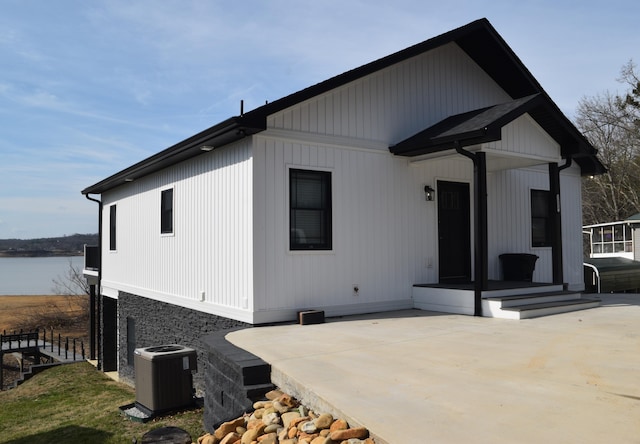 exterior space with central AC, a patio area, and a water view