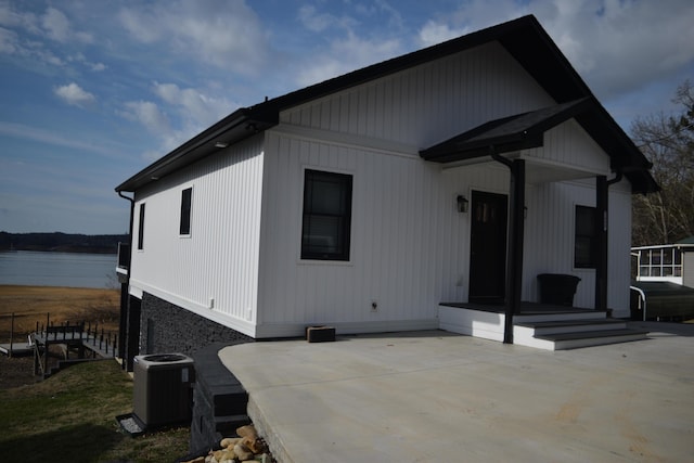 view of front of property featuring cooling unit, a patio area, and a water view