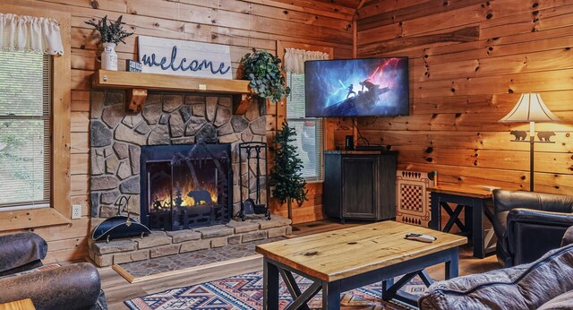 living room featuring a stone fireplace, wooden walls, and hardwood / wood-style floors